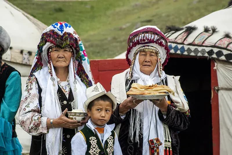 Hosts by a yurt greeting guests with bread