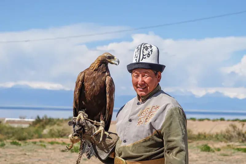 An eagle hunter with his golden eagle on the shore of Issyk-Kul